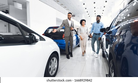 Car Selling Business. Manager Showing Luxury Automobile To Afro Spouses In Automobile Dealership Center. Panorama - Shutterstock ID 1668929842