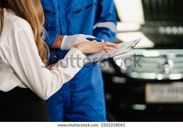Car service and Automobile\
maintenance Concept, Clipboard for repaired item and checking list\
while technician showing to woman customer at automobile service\
center