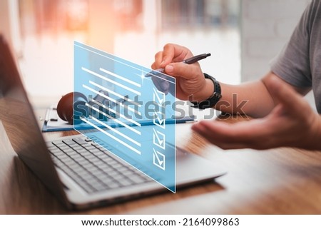 Car service business concept and smart checklist of car service on virtual screen,Close up hand a man holding pen mark on checklist  and use laptop in car service center office and auto part on table