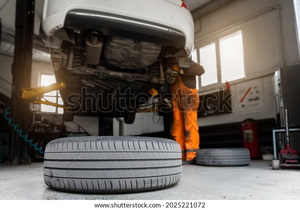 Car\
service center. Bottom behind pov vehicle raised on lift technician\
worker perform diagnosticas and inspection at maintenance station .\
Automobile repair and check up at workshop\
garage
