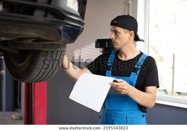 Car\
service employe inspect car. Mechanic inspects the car\
undercarriage way and makes a note on his inspection sheet.\
Automobile service, car mechanic. Modern\
workshop