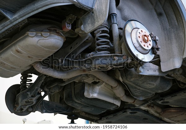 A car in a car service is lifted on a lift for repair.\
Bottom view of the car. Vehicle underbody, rear suspension elements\
and muffler.  
