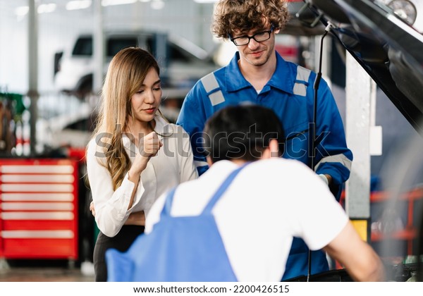 Car service and maintenance\
Concept, Asian woman customer looking the engine while Auto\
Mechanic explaining and showing the point at vehicle part for\
repair