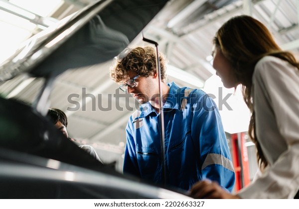 Car service and maintenance\
Concept, Auto repairman showing and explaining the point at vehicle\
part for repair to Asian woman customer at garage\
shop