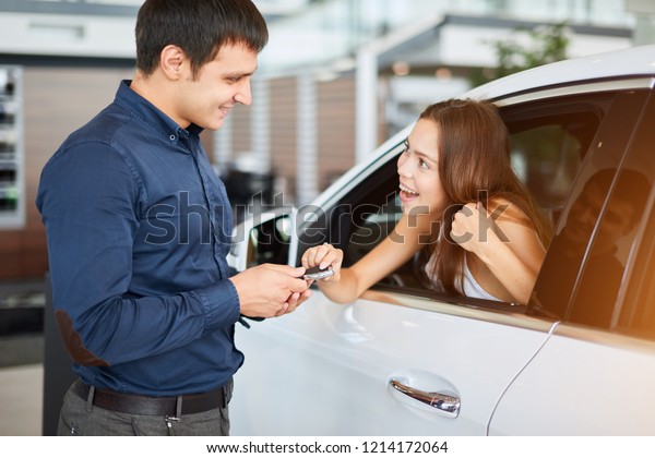 Car\
service manager handing happy young female driver automobile keys.\
Auto repair. Car Trade and Sale. Car Service\
Concept