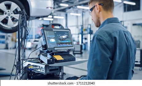 Car Service Manager or Mechanic is Running an Interactive Diagnostics Software on an Advanced Computer. Specialist Inspecting the Vehicle in Order to Find Broken Components and Errors in Data Logs. - Shutterstock ID 1711212040