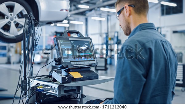 Car Service Manager or Mechanic is Running an\
Interactive Diagnostics Software on an Advanced Computer.\
Specialist Inspecting the Vehicle in Order to Find Broken\
Components and Errors in Data\
Logs.