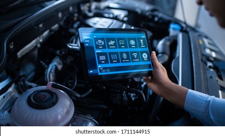 Car Service Manager Or Mechanic Uses A Tablet Computer With A Futuristic Interactive Diagnostics Software. Specialist Inspecting The Vehicle In Order To Find Broken Components In The Engine Bay.