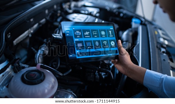 Car Service Manager or Mechanic Uses a Tablet
Computer with a Futuristic Interactive Diagnostics Software.
Specialist Inspecting the Vehicle in Order to Find Broken
Components In the Engine
Bay.