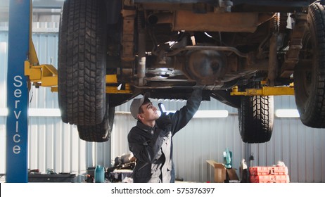 Car Service - A Mechanic Checks The Suspension Of SUV, Wide Angle