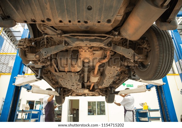 Car service - a mechanic checks the suspension of\
SUV, wide angle