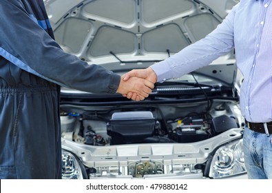 Car service. Mechanic and customer shaking hands. Excellent cooperation between car mechanic and customer. 