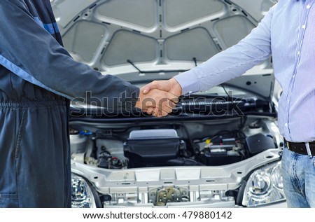 Car service. Mechanic and customer shaking hands. Excellent cooperation between car mechanic and customer. 