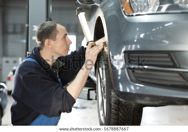 Car service mechanic repairing and maintenance a\
lifted checks the suspension Car repair and maintenance concept at\
car service center