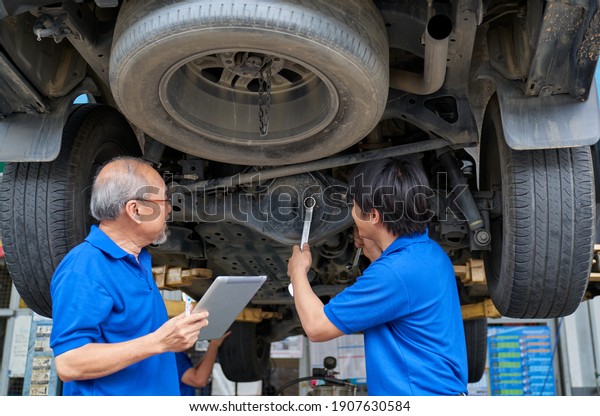 Car service with mechanical team\
for check suspension of SUV car by laptop on crane\
station