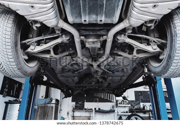 Car\
service. A car on a hydraulic lift in the process of repair. Repair\
of motor vehicles. View of the bottom of the\
machine