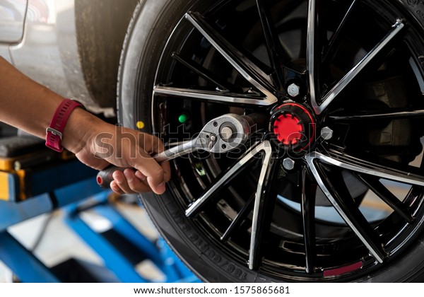 Car service, repair\
and maintenance concept - auto mechanic man changing tire in auto\
repair shop.