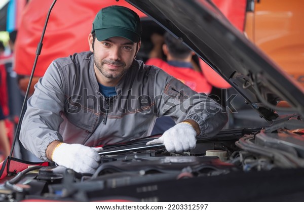 car service, repair, maintenance concept - Arab\
auto mechanic man or Smith Checkingrepair machine at workshop\
warehouse, technician doing the checklist for repair machine a car\
in the garage
