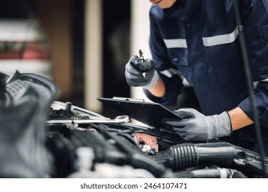 Car service, repair, maintenance concept,auto mechanic man or Smith writing to the clipboard at workshop, technician doing the checklist for repair machine a car in the garage,banner.
