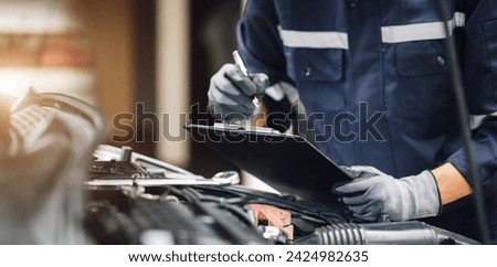 Car service, repair, maintenance concept,auto mechanic man or Smith writing to the clipboard at workshop, technician doing the checklist for repair machine a car in the garage,banner.