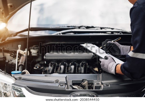 Car service, repair, maintenance\
concept,auto mechanic man or Smith writing to the clipboard at\
workshop, technician doing the checklist for repair machine a car\
in the garage,banner.