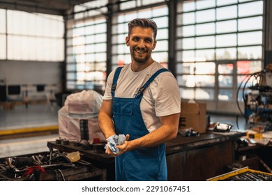 Car service, repair, maintenance and people concept - auto mechanic man or smith cleaning his hands with wipe at workshop
