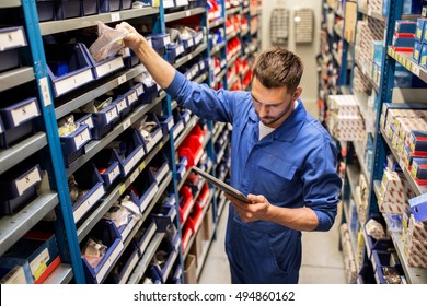 car service, repair, maintenance and people concept - auto mechanic man or smith with tablet pc computer looking for spares at workshop or warehouse - Shutterstock ID 494860162