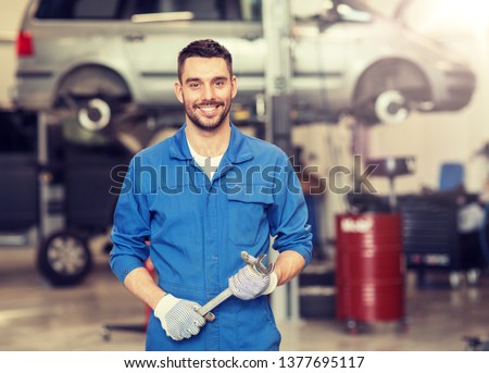 car service, repair, maintenance and people concept - auto mechanic man or smith with wrench at workshop