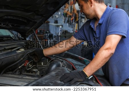 Car service, repair, maintenance and people concept - auto mechanic looking for a malfunction in the car engine. Mechanic hands checking up of serviceability of the car in open hood, close up.
