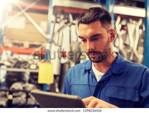 car service, repair, maintenance and people\
concept - auto mechanic man or smith with tablet pc computer at\
workshop or warehouse