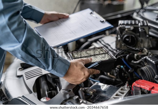 Car\
service staff hold air filter of car engine and checklist in car\
service vehicle mileage check : Service\
concept