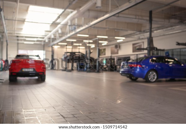 Car service station blurred background, copy\
space. Modern vehicles at repair workshop. Insurance, automobile\
maintenance concept