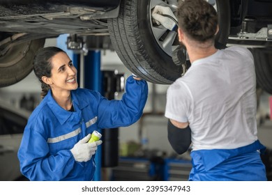 Car service technicians examine, analyze, diagnose wheel and tire issues in garage workshop. Using precise tools to detect, troubleshoot, repair problems, ensuring optimal balancing and alignment. - Shutterstock ID 2395347943