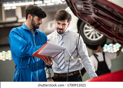 Car Service, Vehicle Repair Concept : Car Service Technician Explaining Checking List Or Repaired Item To Vehicle Owner Customer After Sending Car For Repairing Or Check At Automobile Service Center.