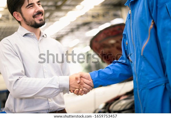 Car\
service, vehicle repair concept : Vehicle owner customer shaking\
hand with car service technician after sending his car for\
repairing or check at automobile service\
center.