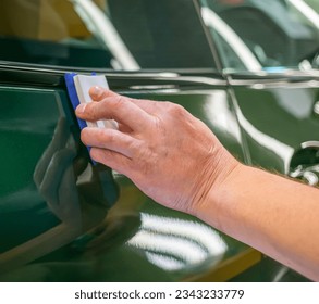 Car service worker applying nano coating on a car detail close-up.  Closeup of hand coating green car bonnet paint. Automotive ceramics. 
