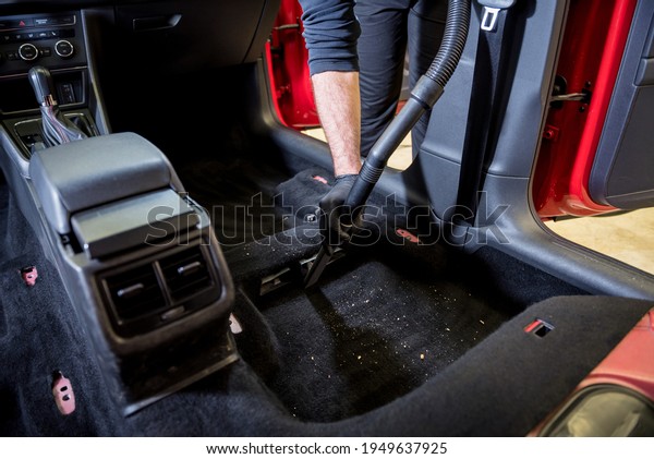 Car service worker cleaning car interior with a\
vacuum cleaner
