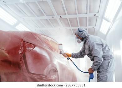 A car service worker coats a car with varnish using compressor. in a special box for painting cars. Automotive paint services, quality auto body shop concept. - Powered by Shutterstock