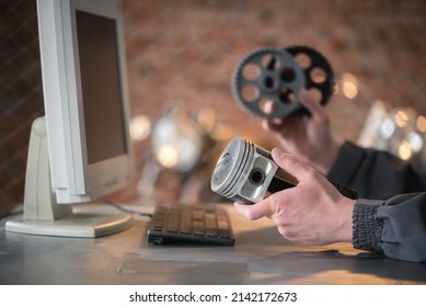 A car service worker with the engine piston and gear wheels in hands sits in front of computer. Online automobile spare parts shop concept. - Shutterstock ID 2142172673