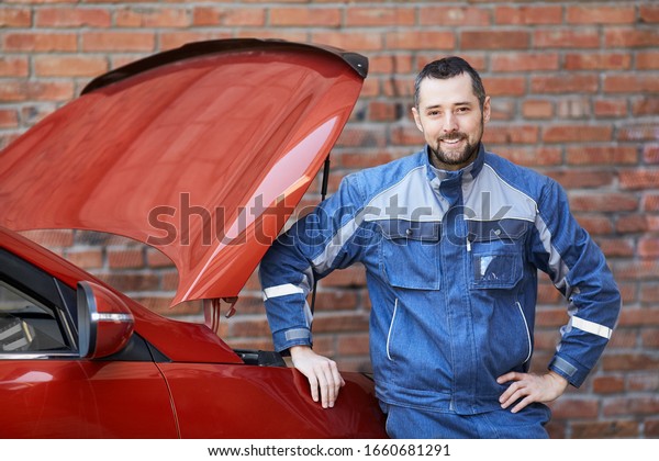Car service worker near the car. Car service\
worker smiles at the\
camera.
