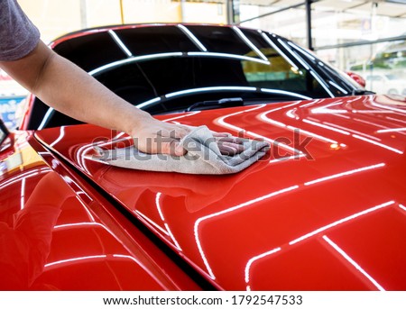 Car service worker polishing car with microfiber cloth.