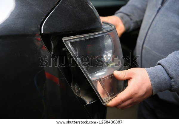 car service worker
removes the rear light on the car.  mechanic's hands remove the
rear light from the car. 