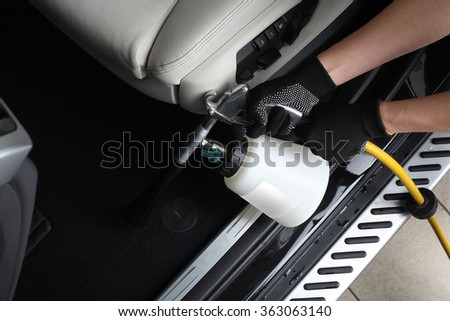 Car service. Worker washing of  interior by a special cleaners under pressure.