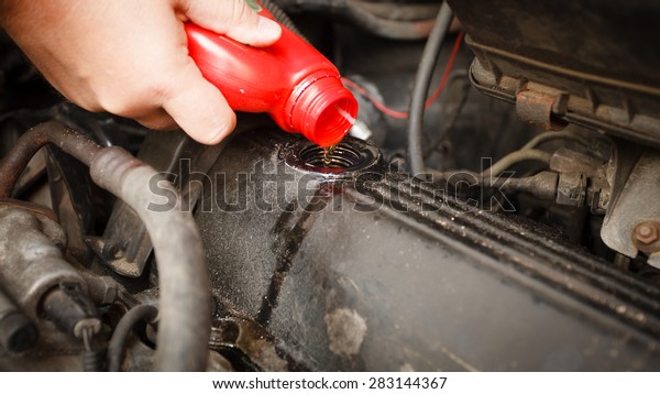 Car servicing mechanic pouring\
oil to engine. Closeup of fresh oil being poured into a\
car.