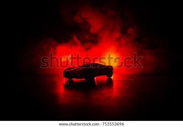 The car in\
the shadows with glowing lights in low light, or silhouette of\
sport car dark background. Selective\
focus