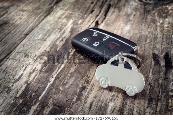 Car shape keyring and keyless entry remote on\
wood background