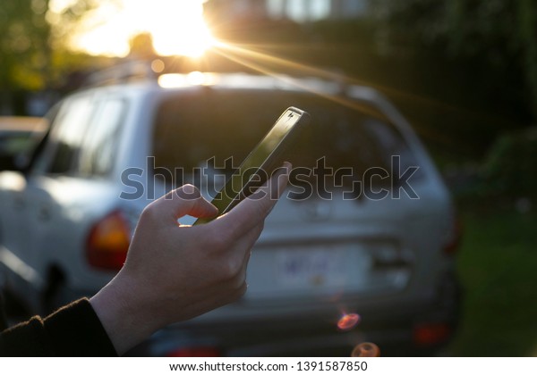 Car sharing\
service or rental concept. Sharing economy and collaborative\
consumption. Customer women suit hand using smart phone with\
silver/ grey cars background.\
