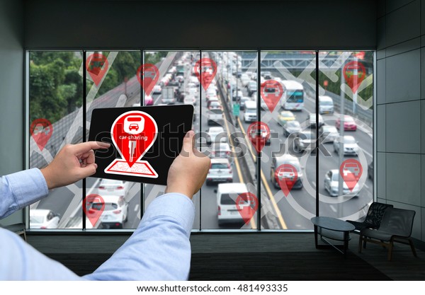 Car\
sharing service or rental concept. Sharing economy and\
collaborative consumption. Man hand holding tablet with icons\
application screen and blur city traffic\
background.