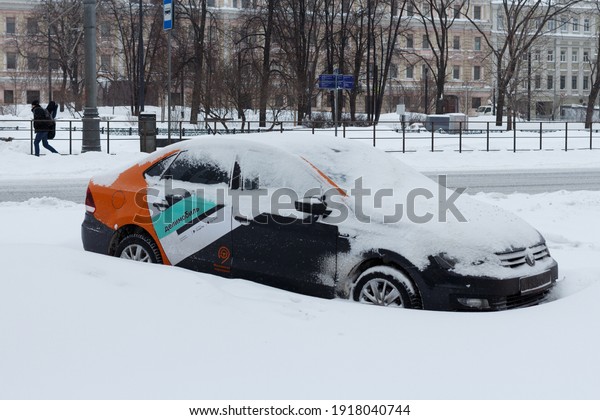 Car sharing car stands\
covered with snow in a parking lot in the city. Moscow, Russia,\
February 13, 2021.