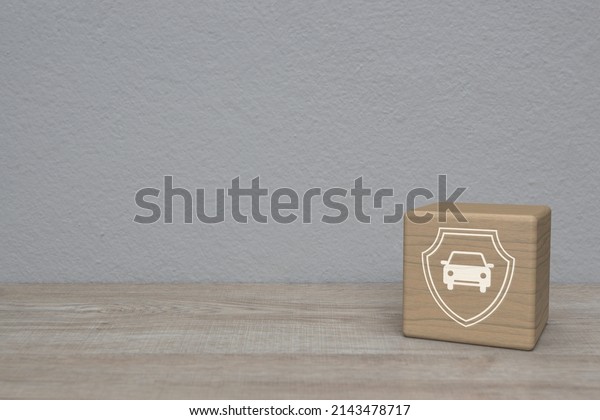 Car with shield flat icon on wood block cube on\
wooden table over white wall background, Business automobile\
insurance concept